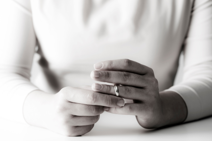 Woman removing her wedding ring as she considers how can she hide money from her husband